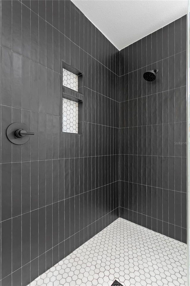 bathroom with tiled shower and a textured ceiling