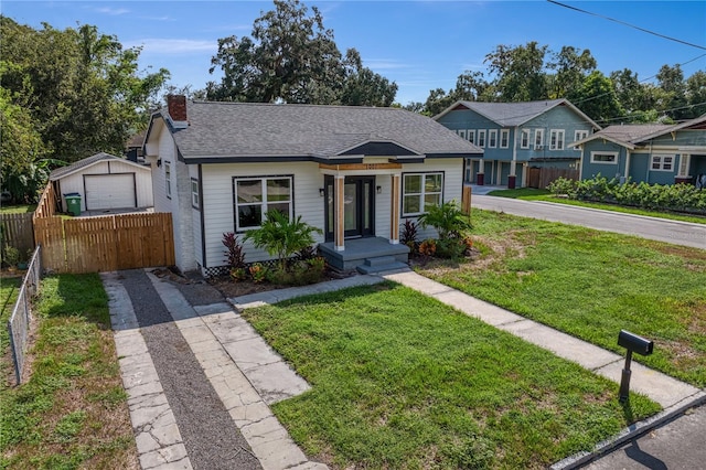 view of front of house featuring a garage, a front lawn, and an outbuilding