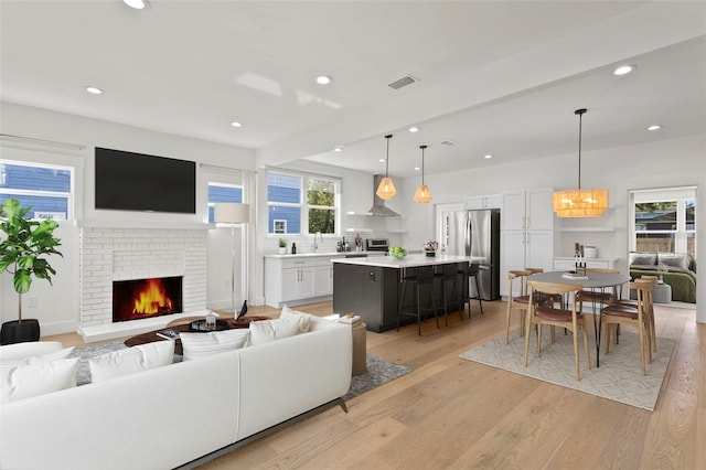 living room with light hardwood / wood-style floors and a brick fireplace