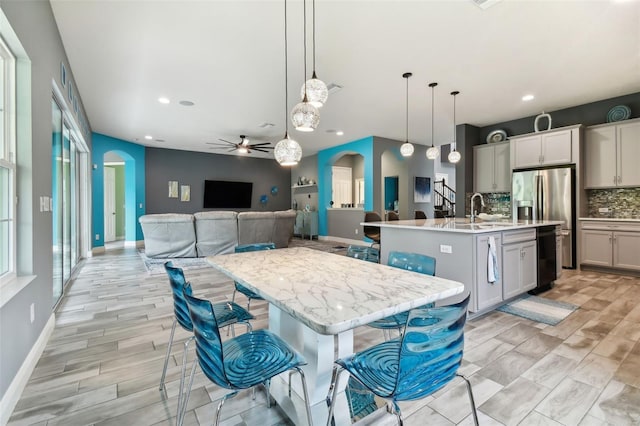 kitchen featuring backsplash, a large island, pendant lighting, a breakfast bar, and ceiling fan