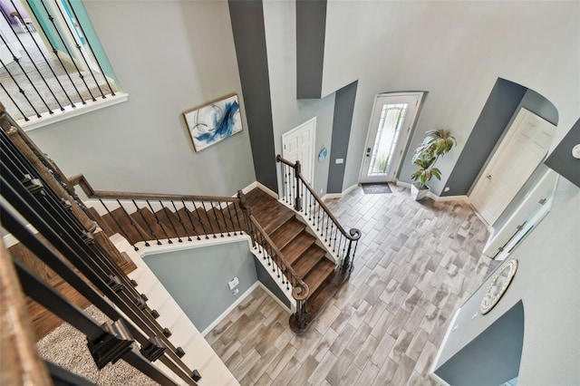 foyer entrance with a towering ceiling and light wood-type flooring