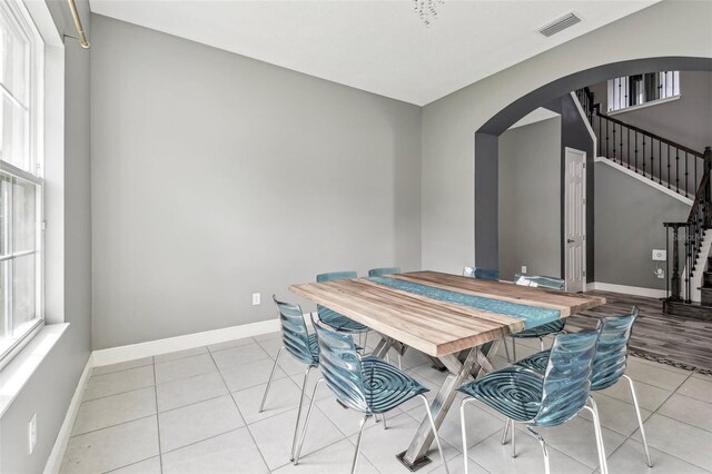 6317 Brevada Ln, Apollo Beach, FL 33572 - dining space with arched walkways, stairs, light tile patterned floors, and baseboards