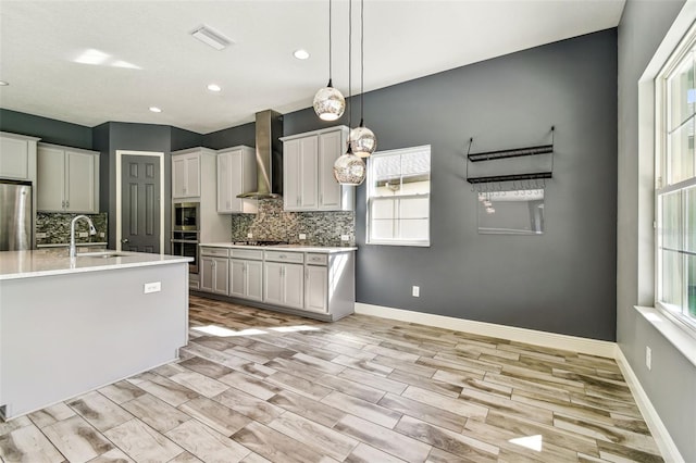 6317 Brevada Ln, Apollo Beach, FL 33572 - kitchen featuring wall chimney range hood, a sink, appliances with stainless steel finishes, decorative backsplash, and light countertops