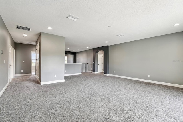 6317 Brevada Ln, Apollo Beach, FL 33572 - unfurnished living room with arched walkways, carpet, a textured ceiling, baseboards, and recessed lighting