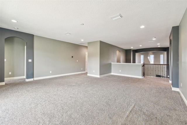 6317 Brevada Ln, Apollo Beach, FL 33572 - carpeted empty room with arched walkways, a textured ceiling, baseboards, and recessed lighting