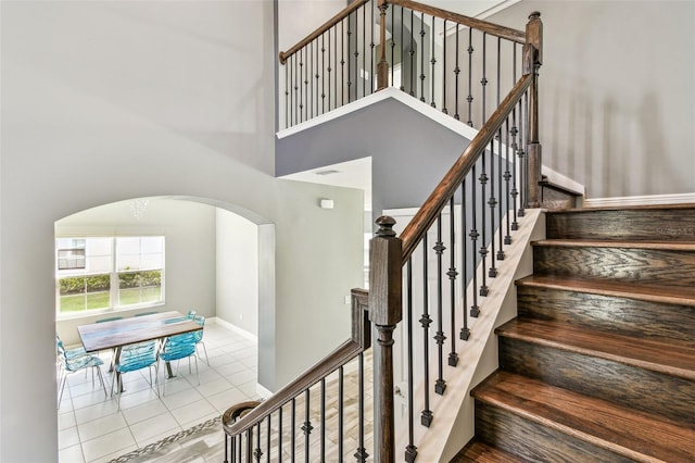 6317 Brevada Ln, Apollo Beach, FL 33572 - staircase with arched walkways, tile patterned flooring, baseboards, and a towering ceiling
