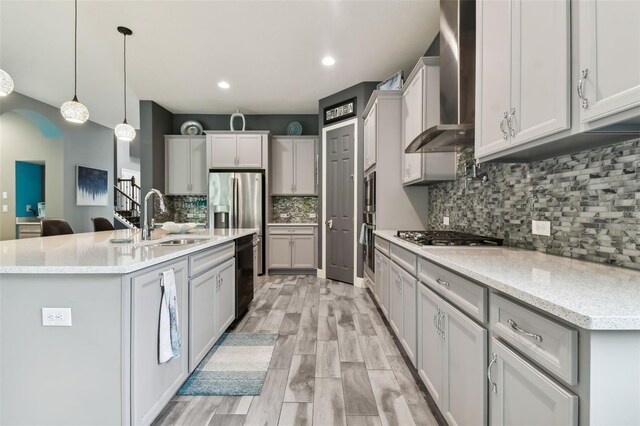 6317 Brevada Ln, Apollo Beach, FL 33572 - kitchen with wall chimney range hood, stainless steel gas cooktop, arched walkways, a sink, and backsplash