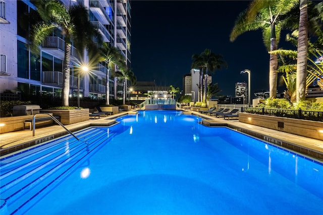 pool at night featuring a patio