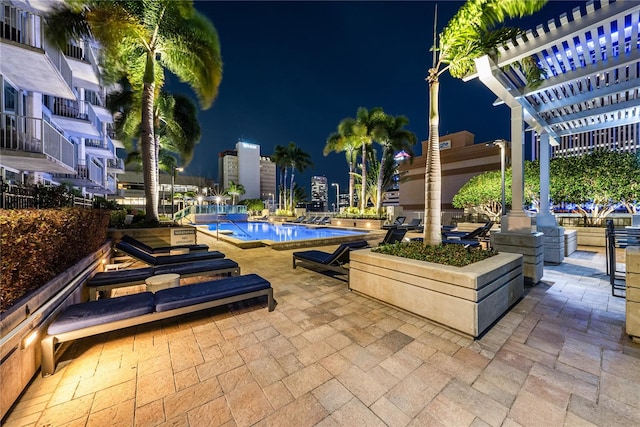 patio at twilight featuring a community pool and a pergola