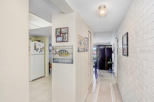 hall featuring brick wall and light tile patterned flooring