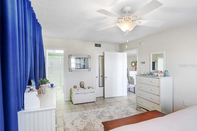 bedroom featuring ceiling fan, light tile patterned floors, and a textured ceiling