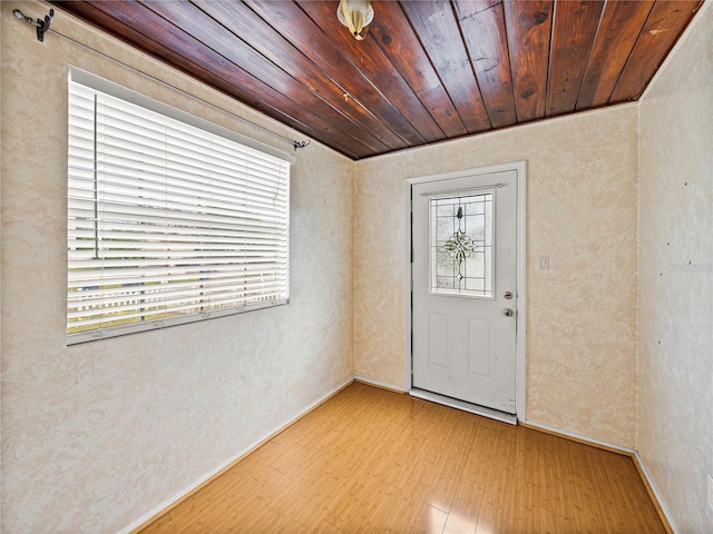 foyer with light wood-type flooring and wooden ceiling