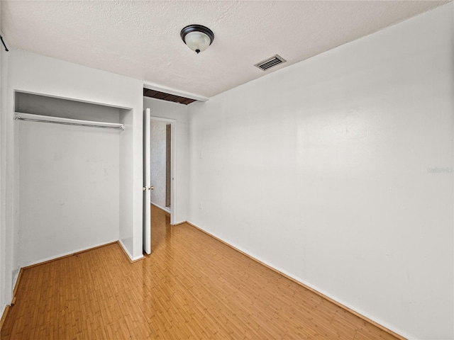 unfurnished bedroom featuring a closet, light wood-type flooring, and a textured ceiling