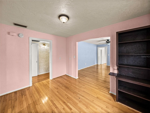 spare room with light hardwood / wood-style floors, ceiling fan, and a textured ceiling