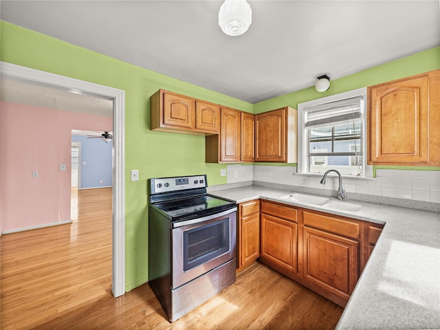 kitchen with sink, ceiling fan, backsplash, light wood-type flooring, and electric stove