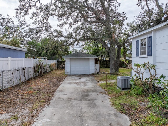 view of yard featuring a garage, central AC unit, and an outbuilding