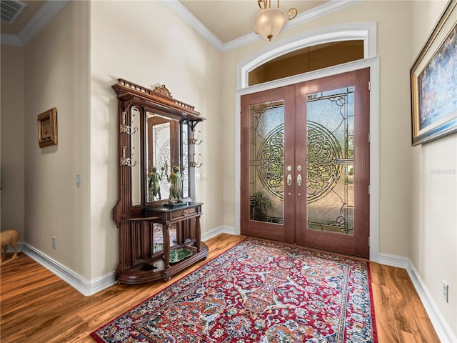 foyer entrance featuring plenty of natural light, wood-type flooring, french doors, and crown molding