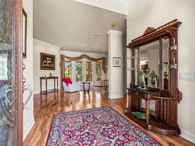 entrance foyer with a textured ceiling, ornamental molding, and light hardwood / wood-style flooring