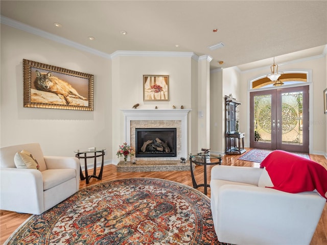 living room with hardwood / wood-style floors, a fireplace, french doors, and ornamental molding