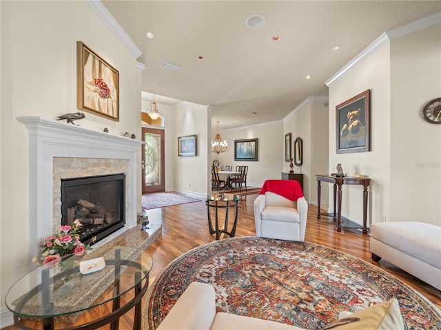 living room featuring hardwood / wood-style flooring, a high end fireplace, a notable chandelier, and ornamental molding