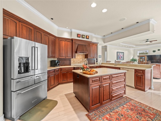 kitchen with stainless steel appliances, kitchen peninsula, custom range hood, ceiling fan, and a kitchen island