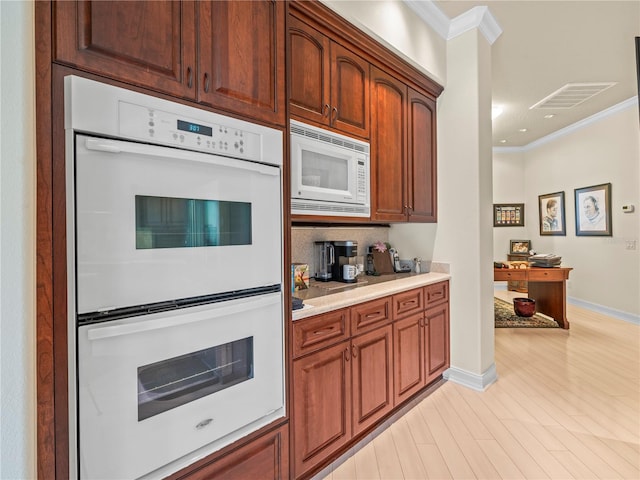 kitchen featuring white appliances, light hardwood / wood-style floors, and ornamental molding