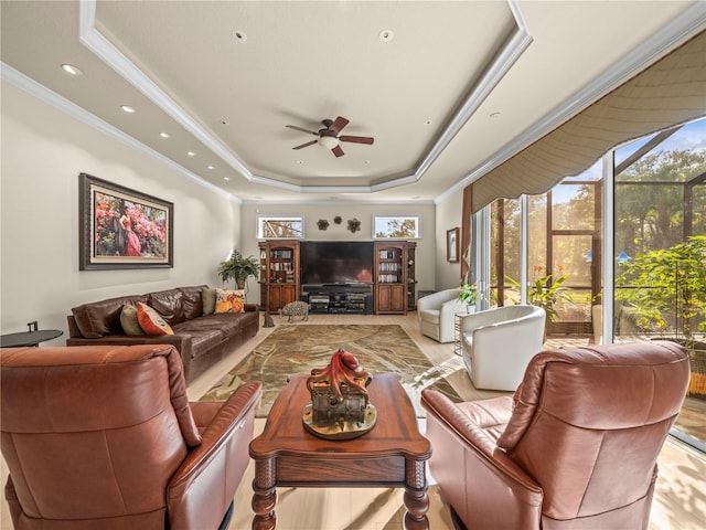 living room featuring ornamental molding, ceiling fan, and a tray ceiling