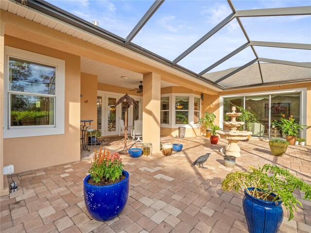 view of patio / terrace with glass enclosure, french doors, and ceiling fan