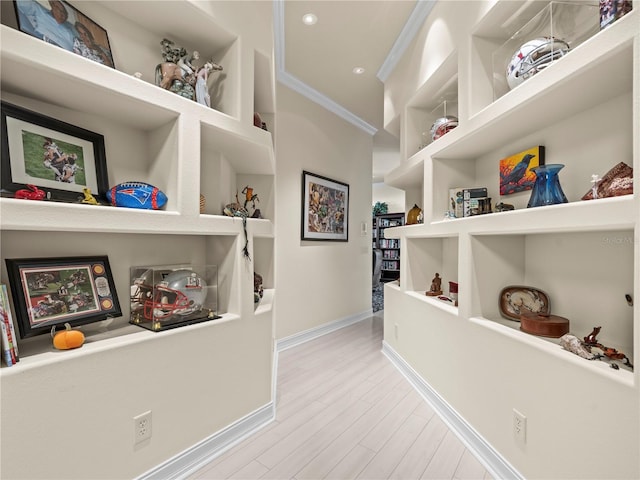 hallway with crown molding and light hardwood / wood-style flooring