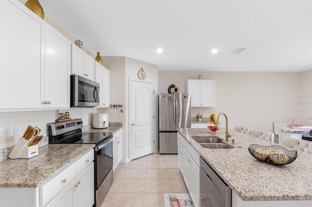 kitchen with stainless steel appliances, light tile patterned flooring, sink, a kitchen island with sink, and white cabinets