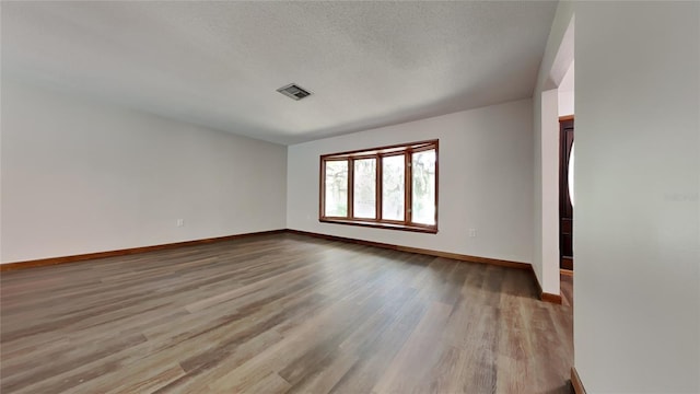 spare room with a textured ceiling and light hardwood / wood-style floors