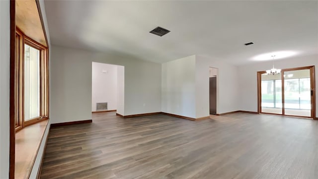 spare room with dark wood-type flooring, a baseboard heating unit, and a notable chandelier