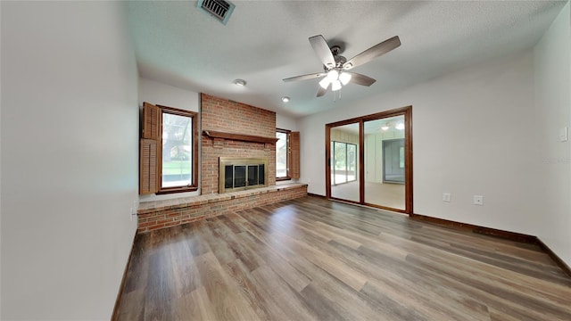 unfurnished living room with hardwood / wood-style flooring, a fireplace, ceiling fan, and a textured ceiling