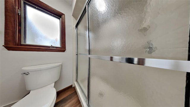 bathroom with hardwood / wood-style floors, an enclosed shower, and toilet