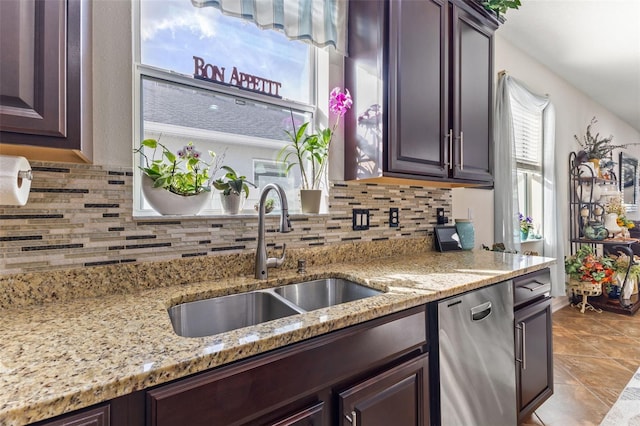 kitchen featuring light stone countertops, stainless steel dishwasher, dark brown cabinets, and sink