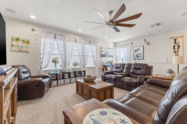 living room featuring light colored carpet, ceiling fan, and a textured ceiling