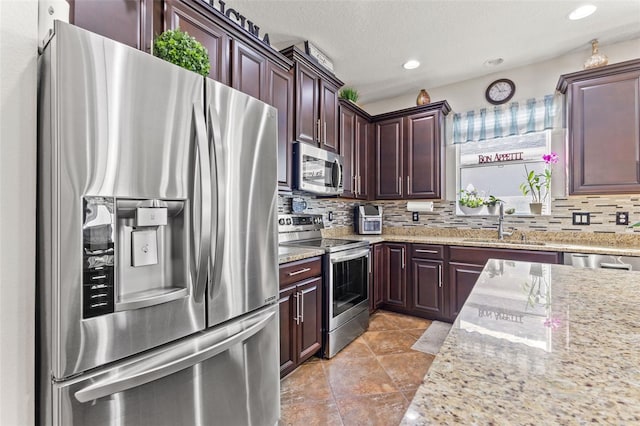 kitchen with stainless steel appliances, sink, tasteful backsplash, and light stone counters