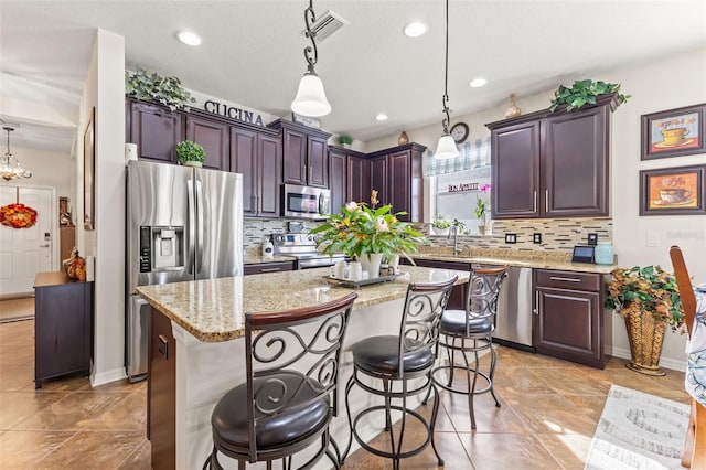 kitchen featuring stainless steel appliances, a kitchen island, backsplash, and hanging light fixtures