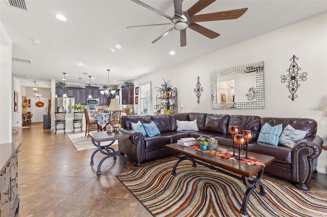 living room featuring tile patterned floors and ceiling fan with notable chandelier