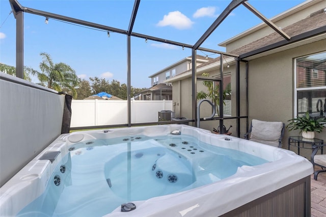 view of patio featuring glass enclosure and a hot tub