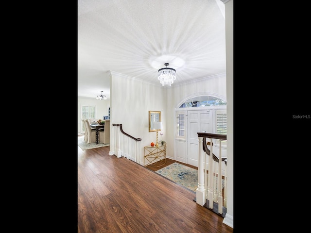 foyer featuring hardwood / wood-style flooring, crown molding, and an inviting chandelier