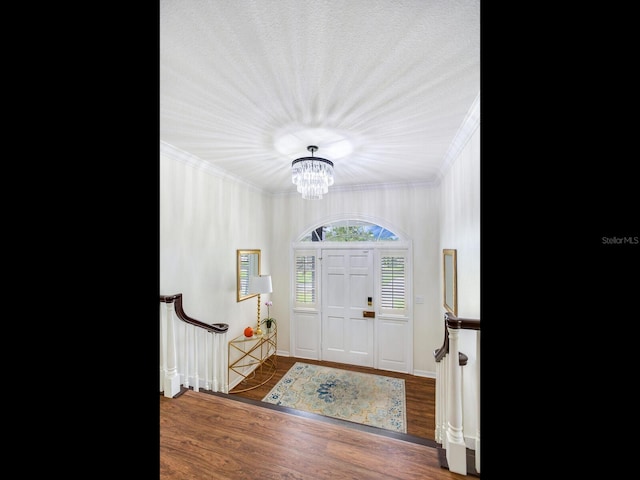 entryway with ornamental molding, dark hardwood / wood-style flooring, and a notable chandelier