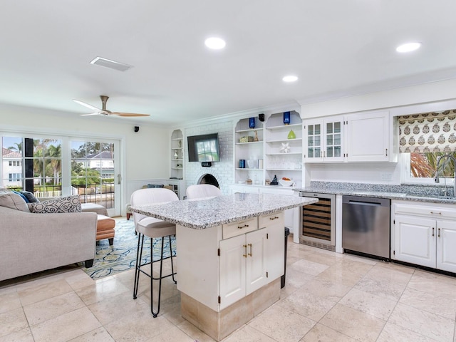 kitchen with white cabinetry, a breakfast bar area, beverage cooler, a center island, and dishwasher