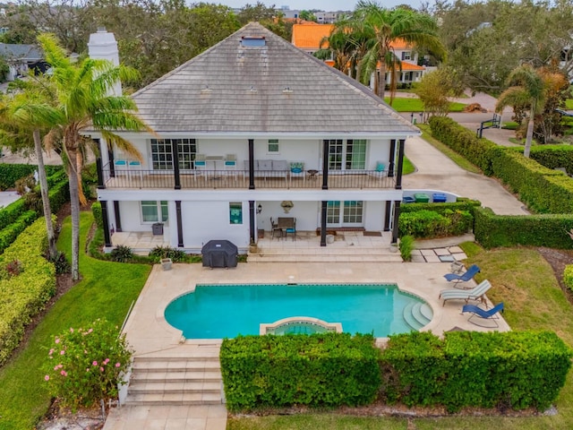 rear view of property featuring a patio, a lawn, and a balcony