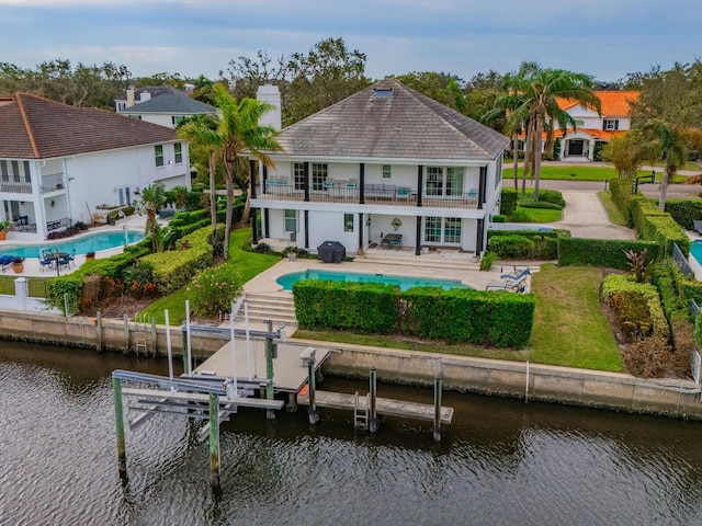 back of house featuring a balcony, a yard, a water view, and a patio area