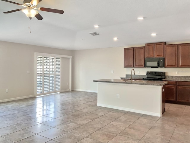 kitchen featuring black appliances, stone counters, sink, ceiling fan, and a kitchen island with sink