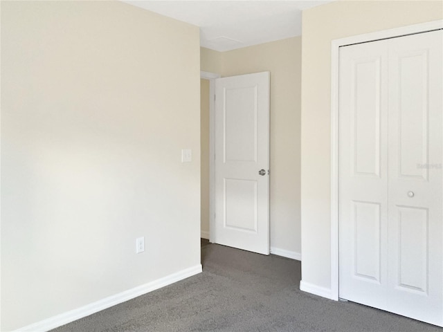 unfurnished bedroom featuring a closet and dark carpet