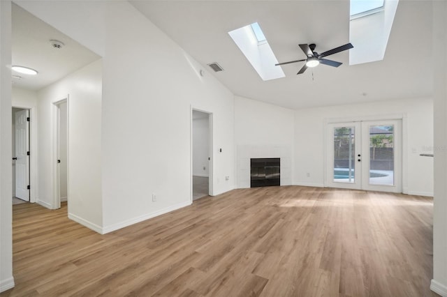 unfurnished living room with french doors, light hardwood / wood-style floors, a tile fireplace, high vaulted ceiling, and ceiling fan