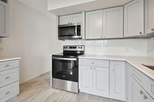 kitchen with appliances with stainless steel finishes and light hardwood / wood-style floors