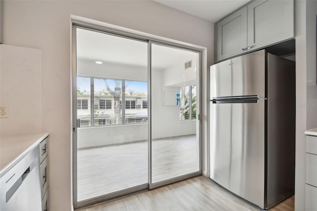 kitchen featuring gray cabinets, light hardwood / wood-style flooring, white dishwasher, and stainless steel fridge